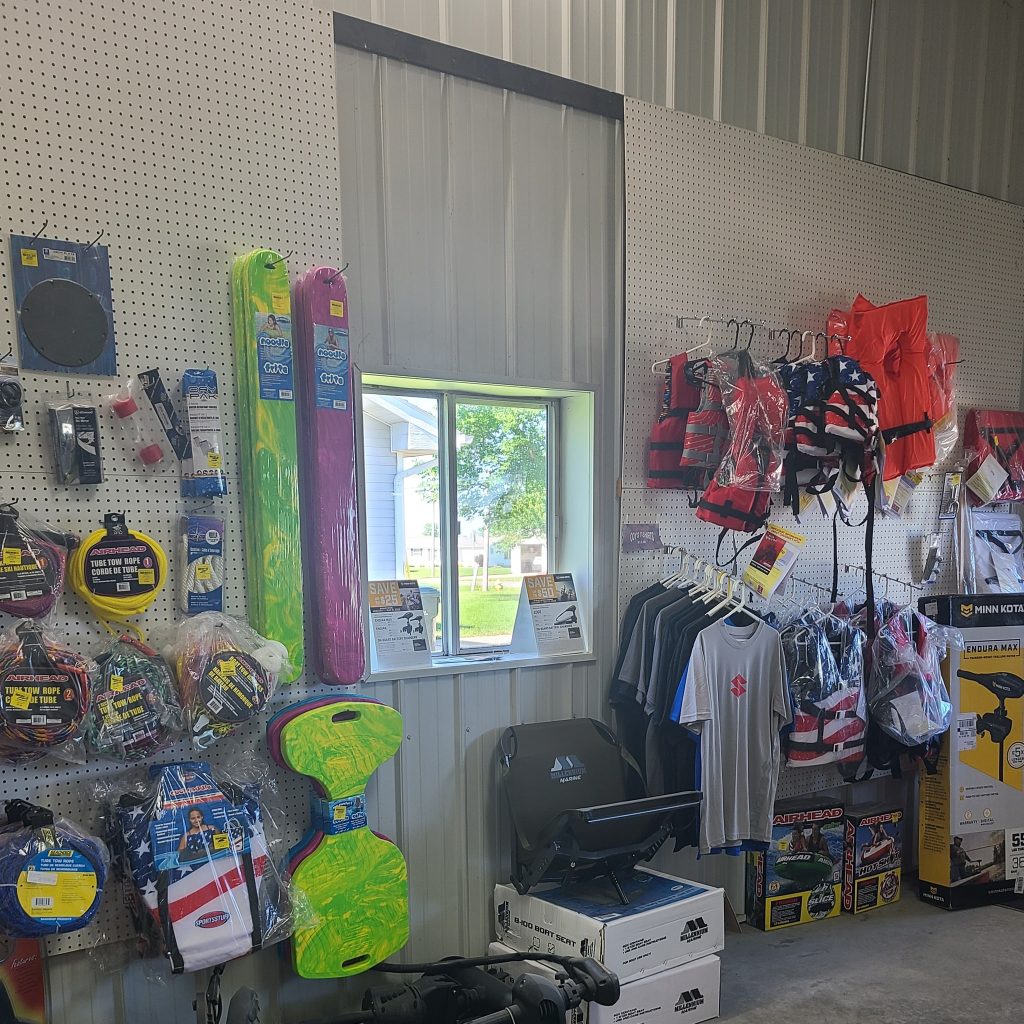 Display of water sports gear, including life jackets, swim boards, and accessories, arranged on pegboards in a store.